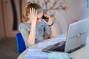 Beautiful young school girl working at home in her room with a laptop and class notes studying in a virtual class. Distance