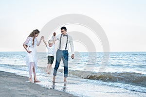 Beautiful young seven walk with a child on the seaside. Happy family on sea beach at resort