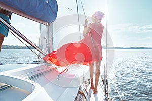 Beautiful young brunette girl in a dress and makeup, summer trip on a yacht with white sails on the sea or ocean in the Gulf