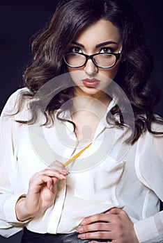 Beautiful young business woman with dark wavy hair and red lips wearing white silk blouse looking direct over her glasses