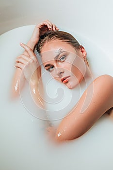 Beautiful young sexy girl with blonde hair wet, exotic makeup, takes bath with milk tan perfect skin, beauty cosmetic