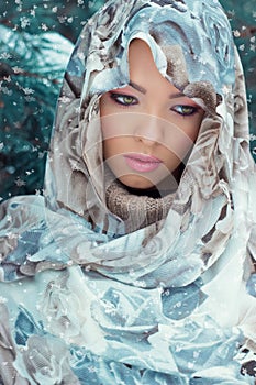 Beautiful young mysterious woman with a scarf on her head standing in the forest near the oil in bright winter day