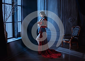 Beautiful young sexy woman vampire in medieval dark castle Red long gothic dress