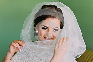 Beautiful young shy bride hiding her face behind veil