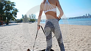 Beautiful young slim athletic woman walking with cute tricolor Welsh Corgi dog on the sand beach at sunny morning.