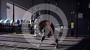 Beautiful young slim woman athlete in a black sportsuit makes the slopes - warm up before training. Front view of a girl