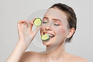 Beautiful young smile woman holding fresh cucumber slices. Skin care, spa, natural beauty and cosmetology concept