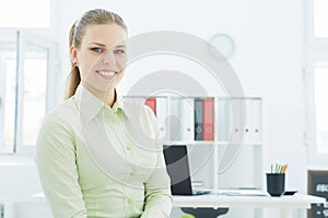 Beautiful young smiling businesswoman on the background of her office.