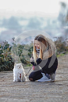 Beautiful young smiling girl strolls with small white dog. German dwarf Spitz. Pomeranian.
