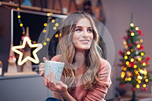 Beautiful young smiling woman at Christmas drinking a cup of tea