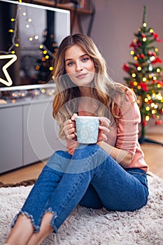 Beautiful young smiling woman at Christmas drinking a cup of tea