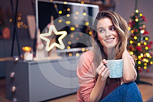 Beautiful young smiling woman at Christmas drinking a cup of tea