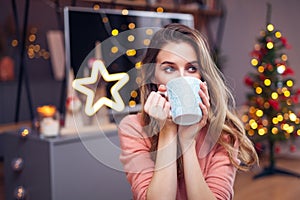 Beautiful young smiling woman at Christmas drinking a cup of tea