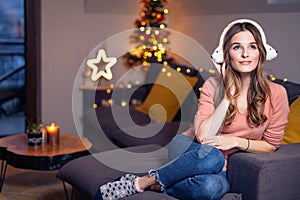 Beautiful young smiling woman at Christmas listening to music