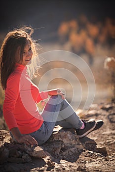 Beautiful young smiling woman enjoys the beauty Valley along the hiking trail posing on the rock on sunny day in Altai