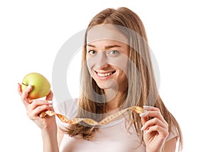 Beautiful young smiling woman holding an apple and measuring centimeter in hands