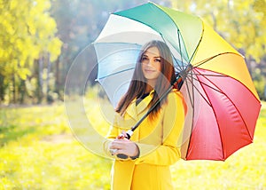 Beautiful young smiling woman wearing a yellow coat with umbrella