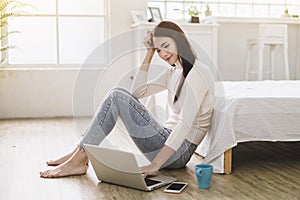 Beautiful young smiling woman working on laptop and drinking coffee at home