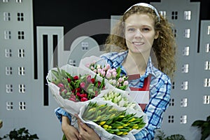 Beautiful young smilling woman florist are selling the bouqet of the tulips in flower shop