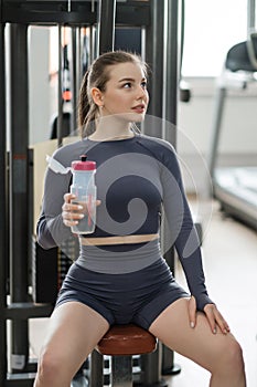 A beautiful young sports caucasian woman in gray sportswear trains in the gym.