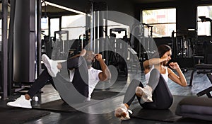 Beautiful young sports couple are doing crunches at the gym.