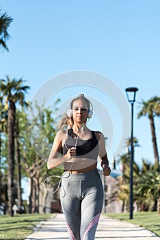 Beautiful young sports Woman running jogging in a park outdoors listening music