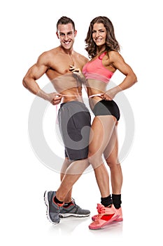 Beautiful young sporty couple with a measuring tape