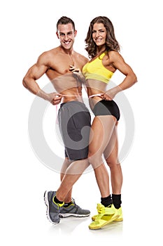 Beautiful young sporty couple with a measuring tape