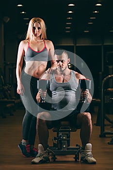 Beautiful young sporty couple showing muscle and workout in gym dumbbell