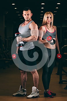 Beautiful young sporty couple showing muscle and workout in gym dumbbell