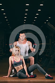 Beautiful young sporty couple showing muscle and workout in gym dumbbell