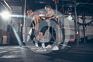 Beautiful young sporty couple training, workout in gym together