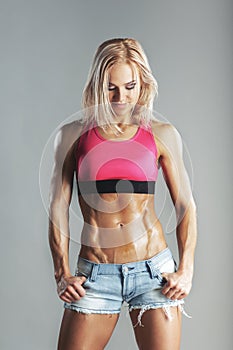 Beautiful young sporty muscular woman looking on her abs