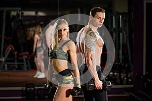 Beautiful young sporty sexy couple showing muscle and workout in gym.