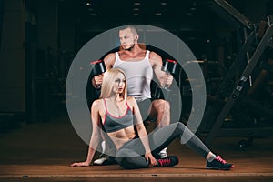 Beautiful young sporty couple showing muscle and workout in gym dumbbell