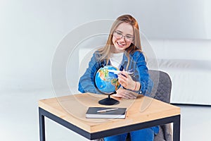 Beautiful young student girl having fun while exploring the globe with model of airplane. Studying geography with globe.