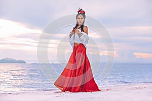 Beautiful young stylish boho woman walking on the beach at sunset