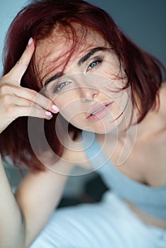 Beautiful young stylish ginger woman with freckles. Fashion portrait of charming girl wearing casual clothes posing at home.