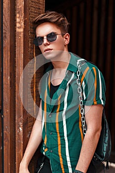 Beautiful young stylish guy with a hairstyle in trendy beach