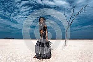 Beautiful young stylish tribal dancer. Woman in oriental costume in desert sands