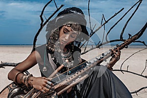 Beautiful young stylish tribal woman in oriental costume playing