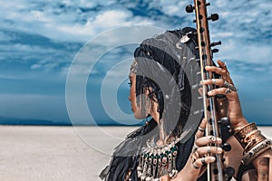 Beautiful young stylish tribal woman in oriental costume playing