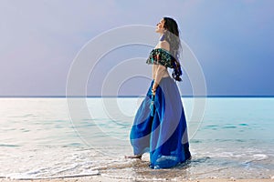 Beautiful young stylish woman in blue skirt on the beach