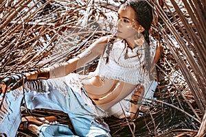 Beautiful young stylish woman at dry palm leaves backgground