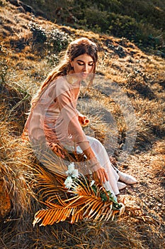 Beautiful young stylish woman on the field at sunset