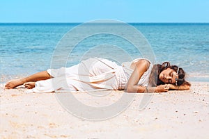Beautiful young stylish woman lying on sand on the beach