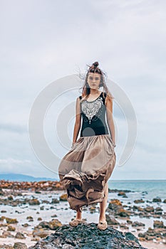 Beautiful young stylish woman in pink skirt walking on the beach