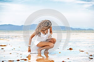 Beautiful young stylish woman in white dress on the beach