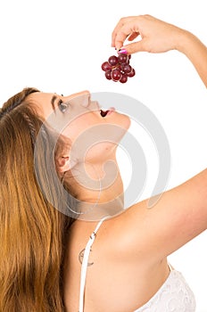 Beautiful young supersticious woman eating grapes