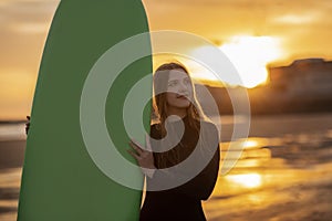 Beautiful Young Surfer Woman Posing With Surfboard On The Beach At Sunset